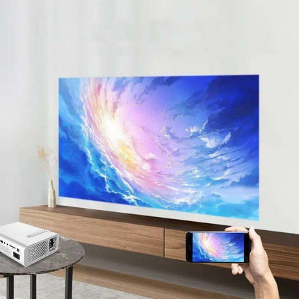 Product shot of a projector projecting an image onto a wall, with a matching image on a smartphone held in a hand.