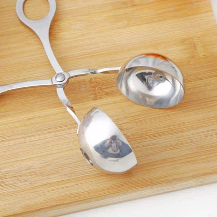 Silver melon baller on a wooden surface.