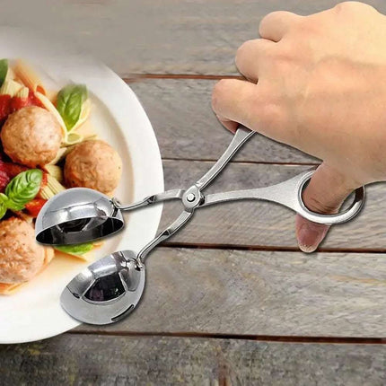 A hand holds stainless steel meatball tongs with meatballs on a plate.